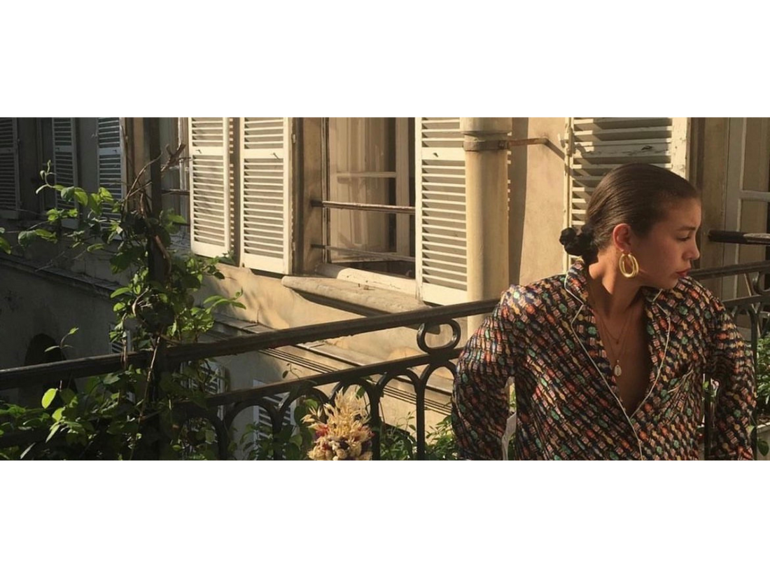 Femme portant une chemise. Assise sur un balcon au soleil. Chemise pouvant être donné à de l'upcycling