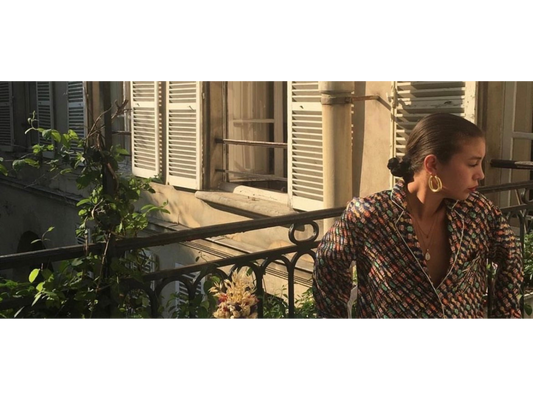 Femme portant une chemise. Assise sur un balcon au soleil. Chemise pouvant être donné à de l'upcycling